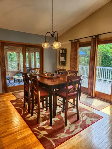 a dining room with wooden floor a chandelier a wooden table and chairs