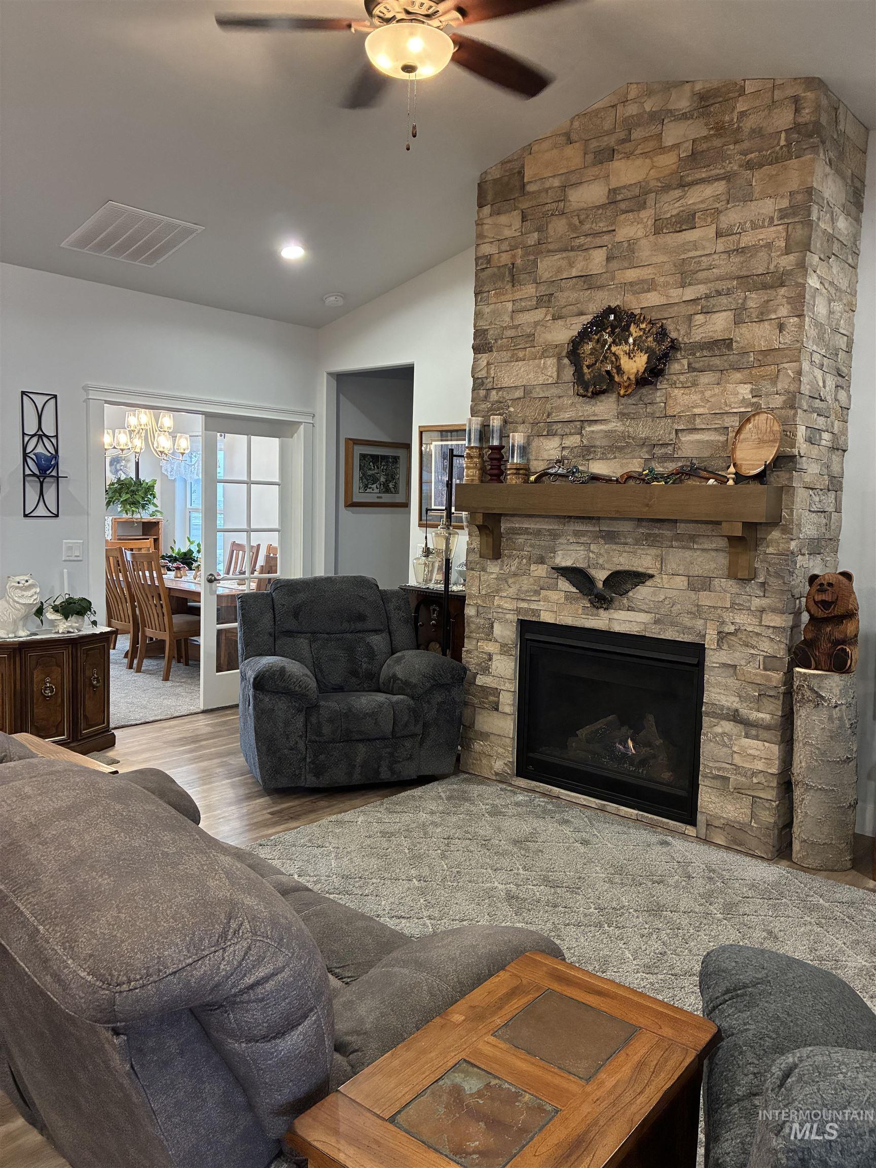 764 Heidi Terrace Kimberly, ID 83341 - Photo 32 of 42 Living area featuring lofted ceiling, a stone fireplace, a ceiling fan, wood finished floors, and a chandelier