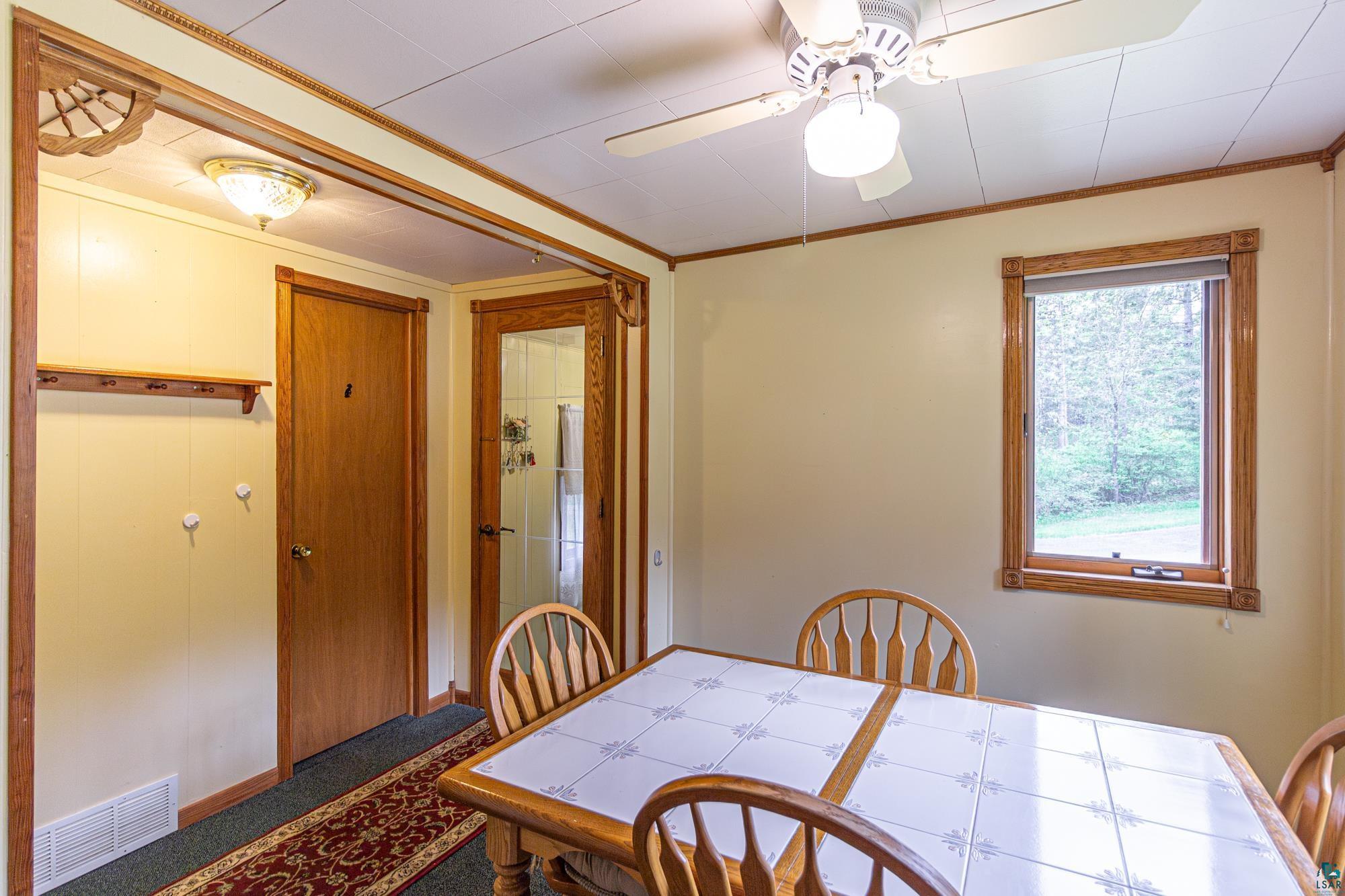 Dining room with ceiling fan, carpet floors, and ornamental molding