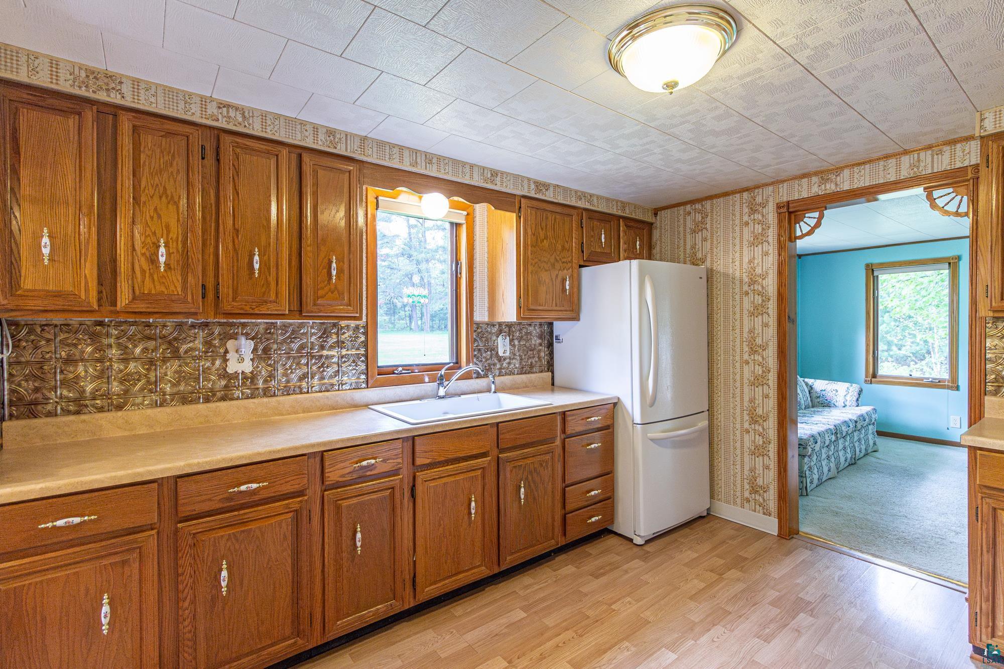 Kitchen with a healthy amount of sunlight, sink, white fridge, and light hardwood / wood-style flooring