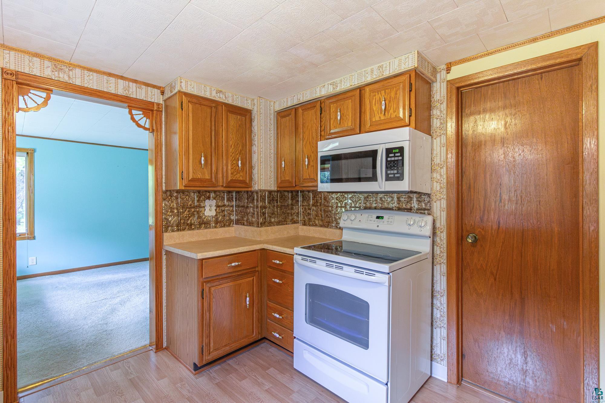 1775 Lookout Road Ely, MN 55731 - Photo 9 of 44 Kitchen with backsplash, white electric range, and light colored carpet