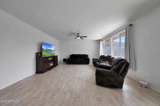a living room with furniture a flat screen tv and a ceiling fan