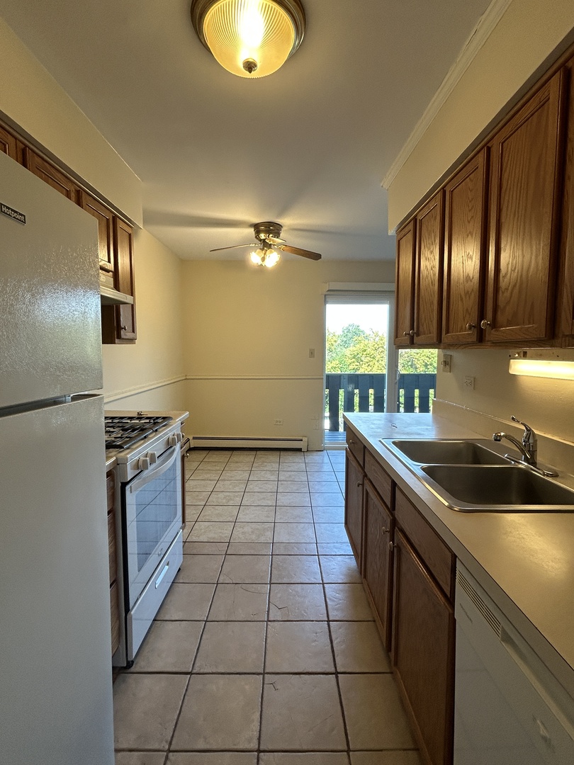1077 Dickens Way, Unit E Schaumburg, IL 60193 - Photo 2 of 7 a kitchen with a sink a stove cabinets and stainless steel appliances