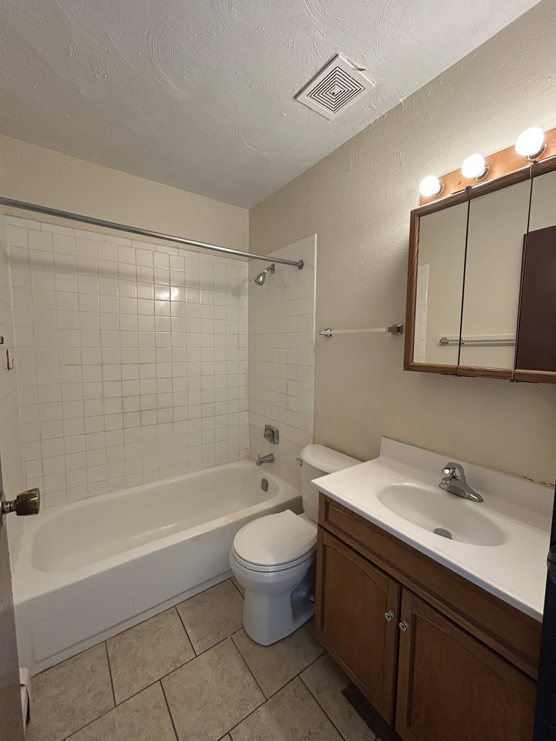1077 Dickens Way, Unit E Schaumburg, IL 60193 - Photo 5 of 7 a bathroom with a sink a toilet and shower
