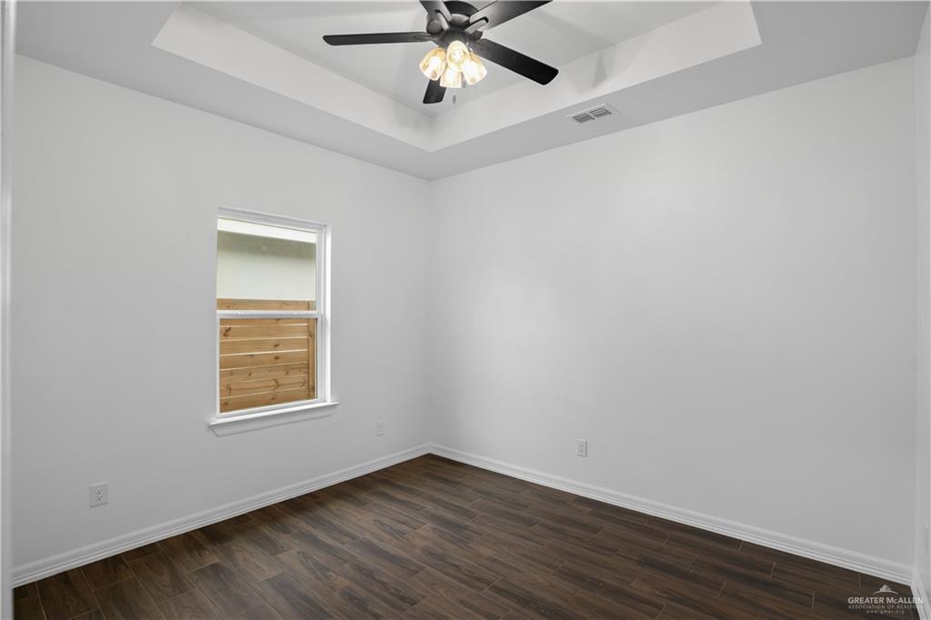 3701 South Solstice Road Edinburg, TX 78542 - Photo 13 of 17 an empty room with wooden floor chandelier fan and windows