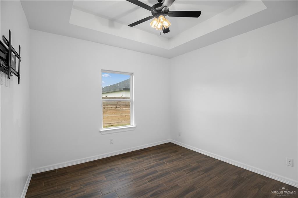 3701 South Solstice Road Edinburg, TX 78542 - Photo 15 of 17 an empty room with wooden floor a ceiling fan and windows