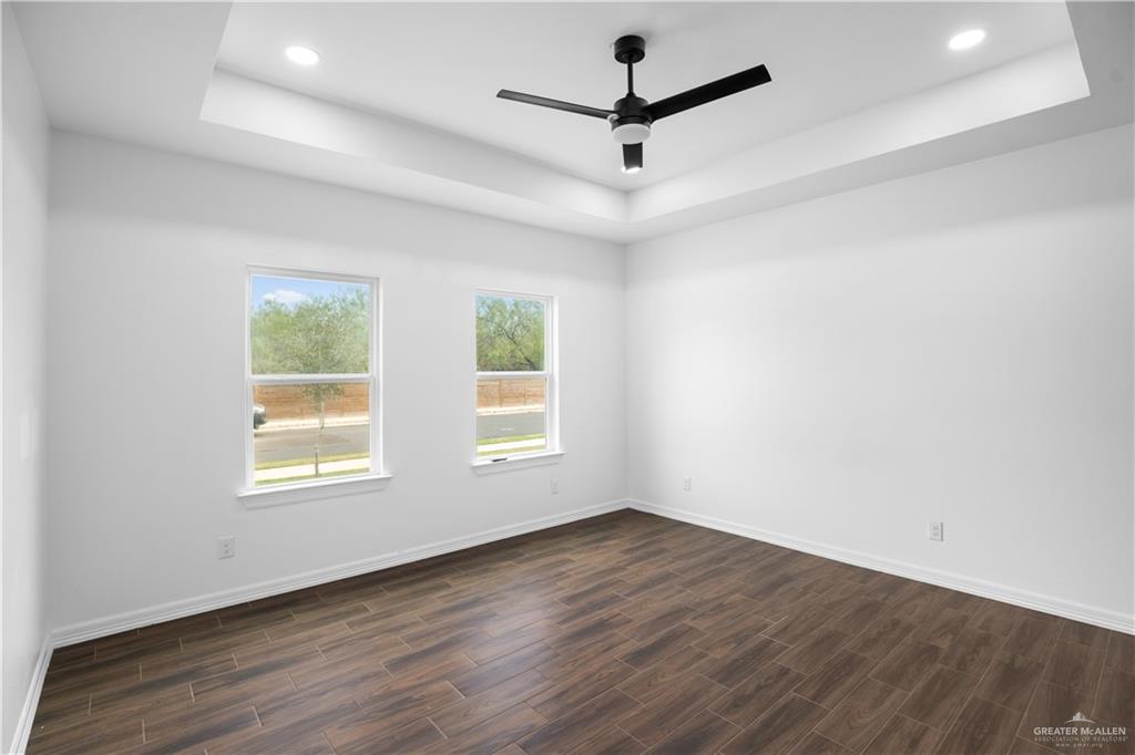 3701 South Solstice Road Edinburg, TX 78542 - Photo 9 of 17 an empty room with wooden floor ceiling fan and windows