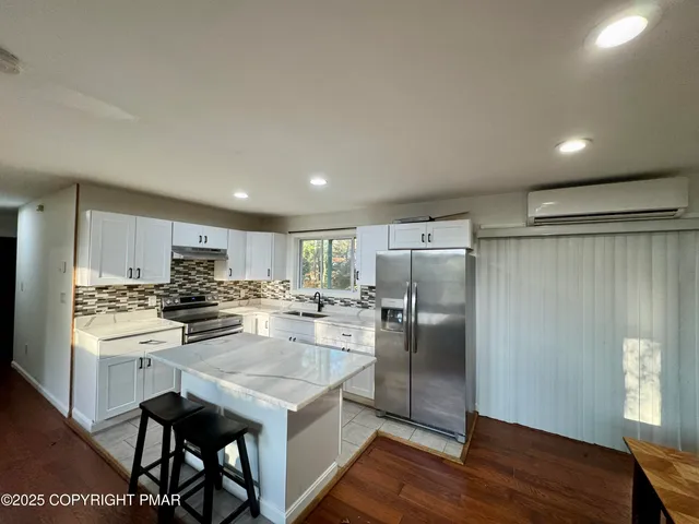 a kitchen with kitchen island a refrigerator stove microwave and cabinets