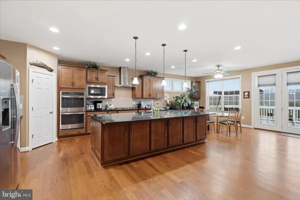 a kitchen with stainless steel appliances granite countertop a sink a stove and a wooden floors