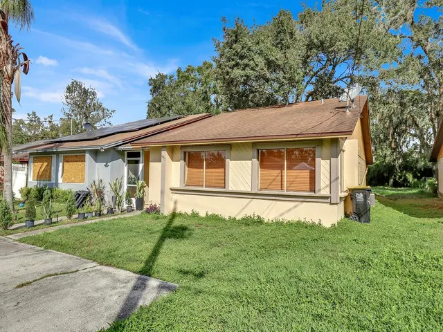 a white house with a big yard and large trees