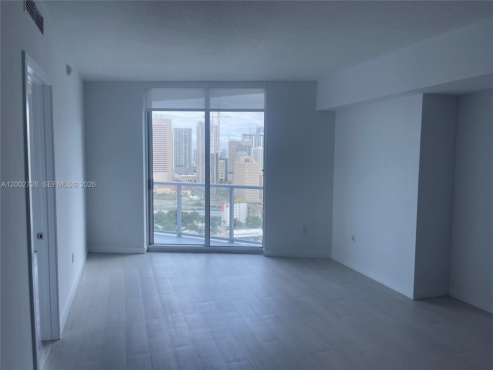 185 Southwest 7th Street, Unit 2705 Miami, FL 33130 - Photo 4 of 5 an empty room with wooden floor and windows