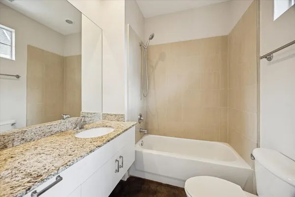a bathroom with a granite countertop tub sink and mirror with shower