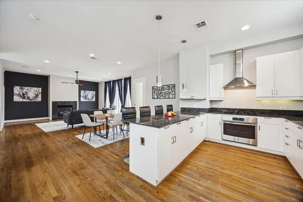 a kitchen with stainless steel appliances granite countertop a stove top oven a sink dishwasher and white cabinets with wooden floor
