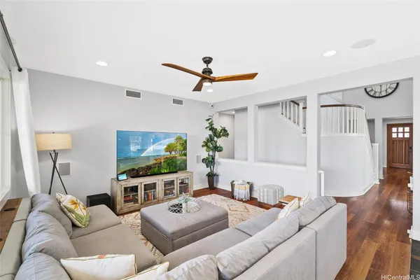a living room with furniture a ceiling fan and a flat screen tv