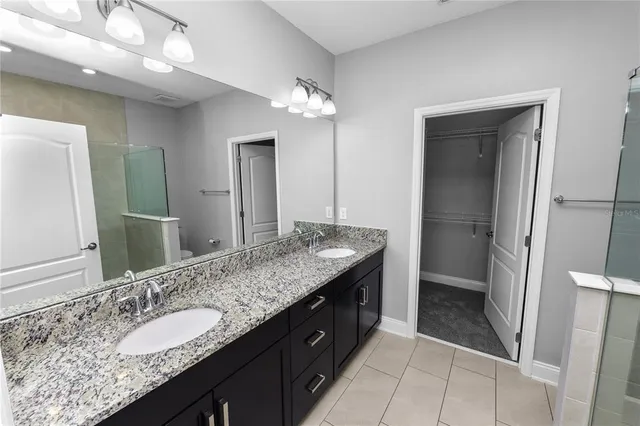 a bathroom with a granite countertop sink a toilet and shower