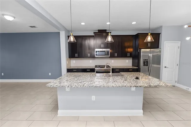 a view of kitchen with stainless steel appliances kitchen island granite countertop a stove a oven a sink and a refrigerator