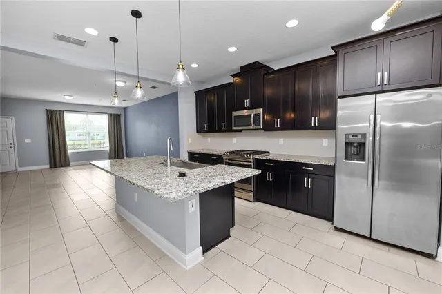 a large kitchen with stainless steel appliances kitchen island granite countertop a refrigerator a sink a stove and a oven