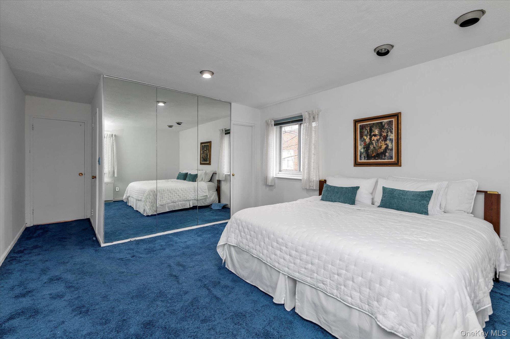 30 Barstow Road, Unit 3A Great Neck, NY 11021 - Photo 12 of 17 a spacious bedroom with a bed and a painting