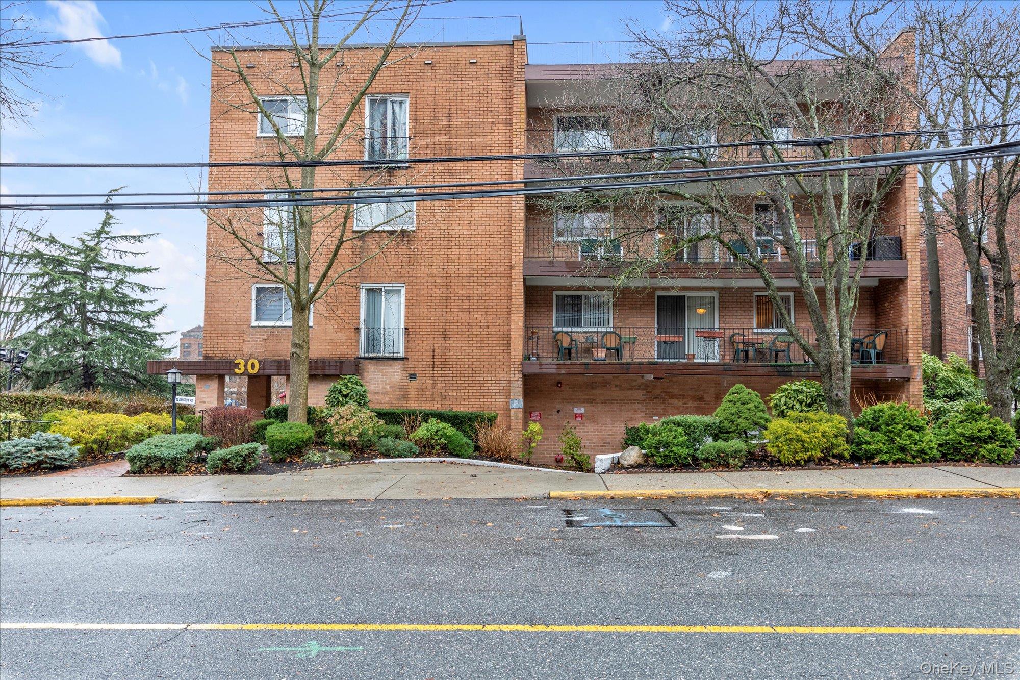30 Barstow Road, Unit 3A Great Neck, NY 11021 - Photo 2 of 17 front view of a brick house with a street