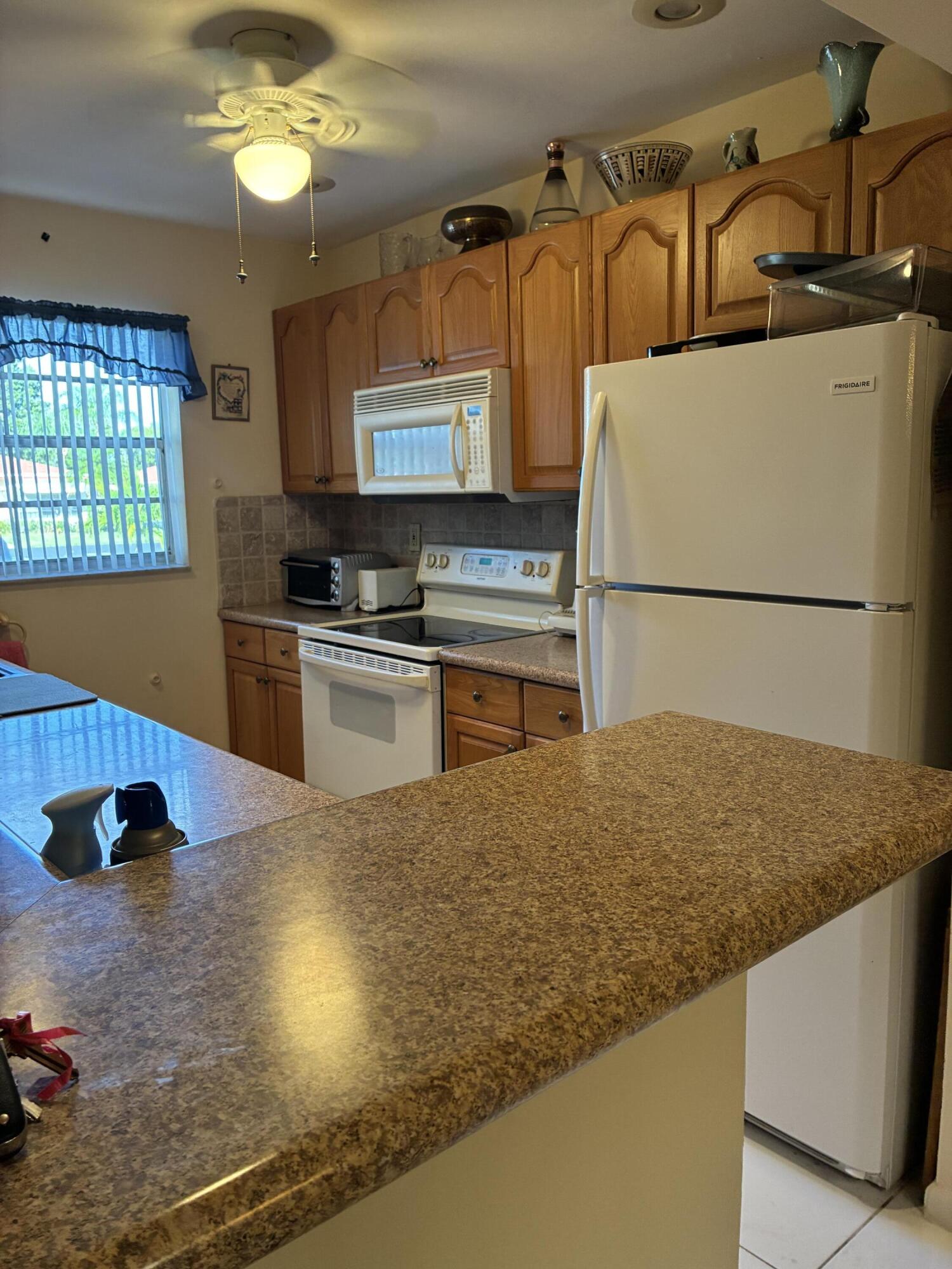 4540 Northwest 3rd Court, Unit C Delray Beach, FL 33445 - Photo 8 of 29 a kitchen with kitchen island a stove a sink and a refrigerator