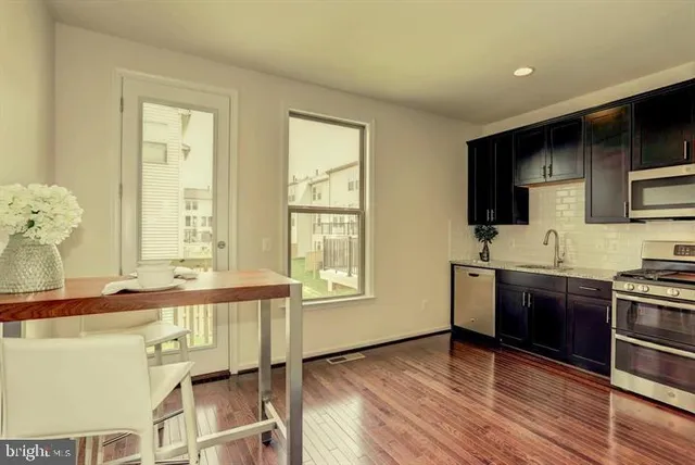 a large kitchen with stainless steel appliances a large counter top a stove and a refrigerator