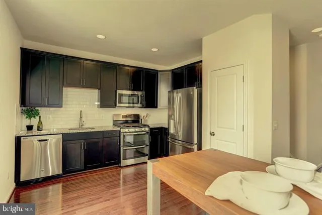 a kitchen with stainless steel appliances granite countertop a refrigerator a sink a stove a microwave and wooden cabinets