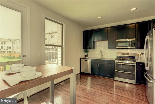 a kitchen with stainless steel appliances a kitchen island hardwood floor sink stove dining table and chairs