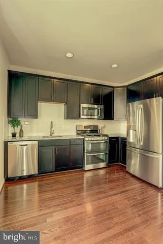 a kitchen with stainless steel appliances kitchen island granite countertop a stove a sink and a refrigerator