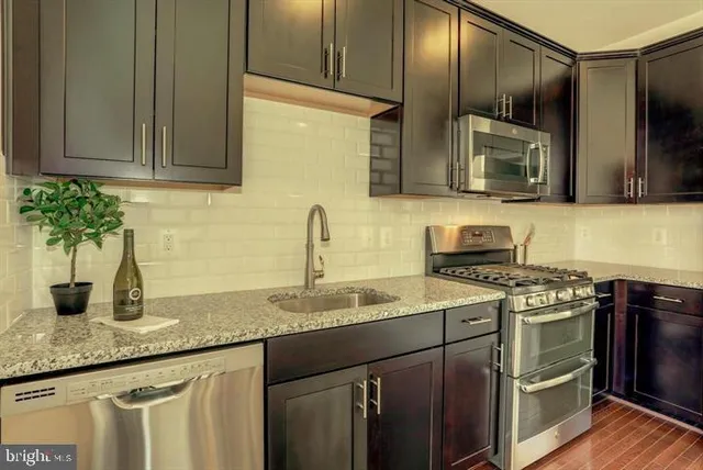 a kitchen with stainless steel appliances granite countertop a sink stove and microwave
