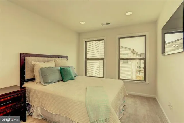 a bedroom with a large bed and two windows