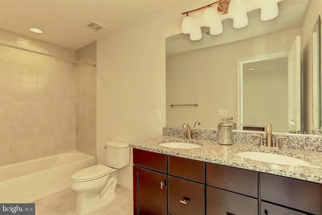 a bathroom with a granite countertop sink a toilet and shower