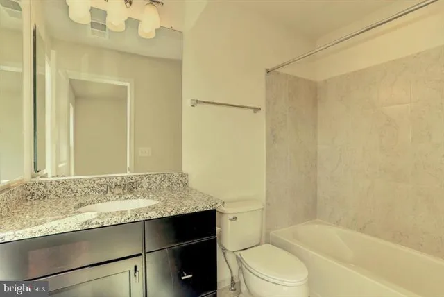 a bathroom with a granite countertop sink toilet and shower