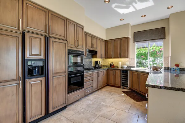 a kitchen with granite countertop a refrigerator stove top oven and sink
