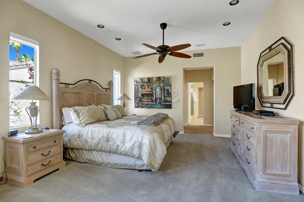 a spacious bedroom with a bed and a flat screen tv