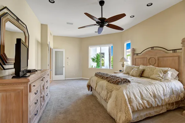 a bedroom with a large bed and a flat tv screen on dresser