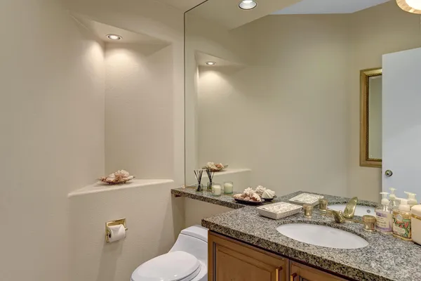 a bathroom with a granite countertop sink a toilet and a mirror
