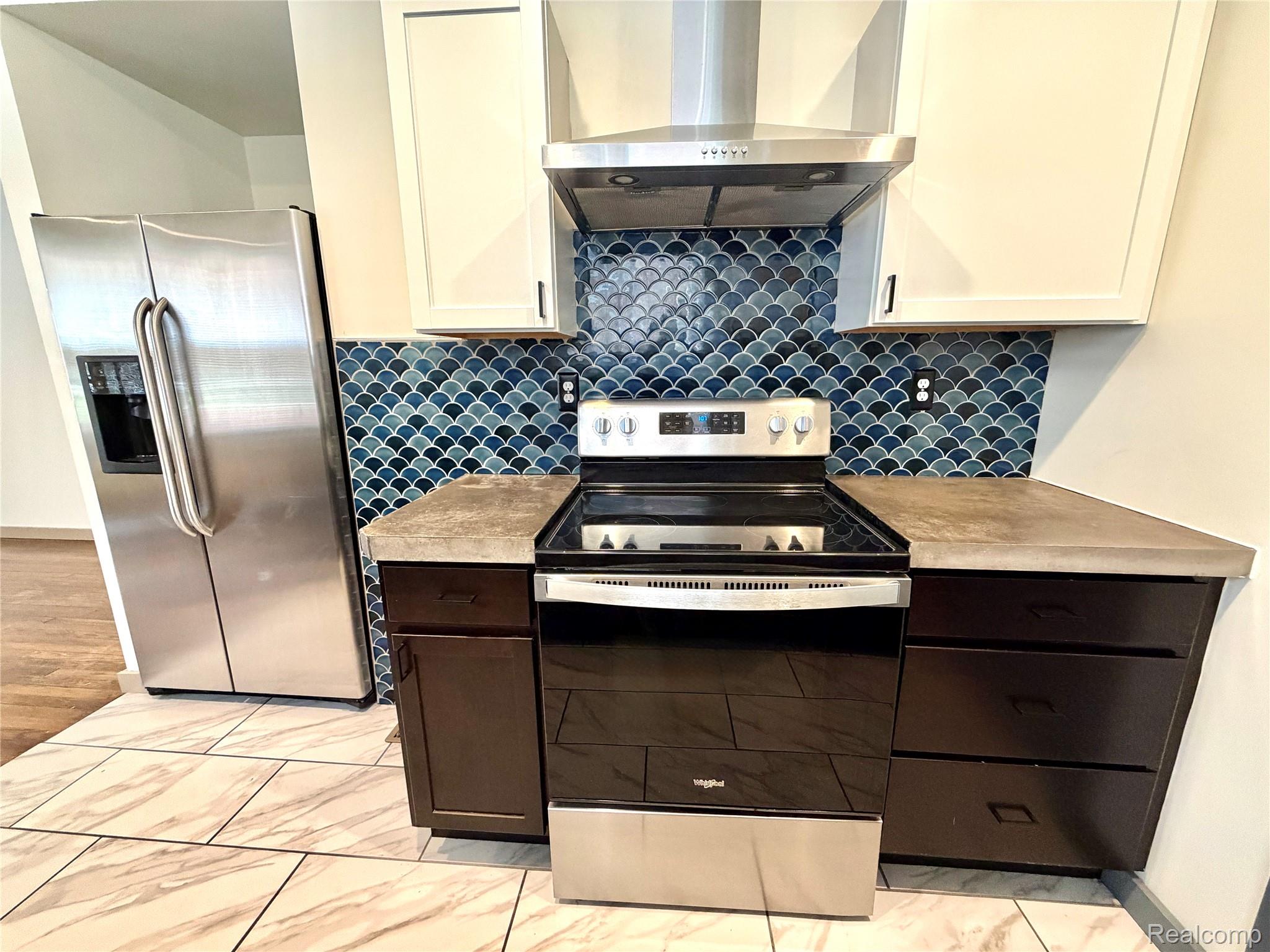 2045 Calvert Avenue Detroit, MI 48206 - Photo 3 of 41 Two tone kitchen with light countertops, stainless steel appliances, light marble finish flooring, backsplash, and two tone color scheme