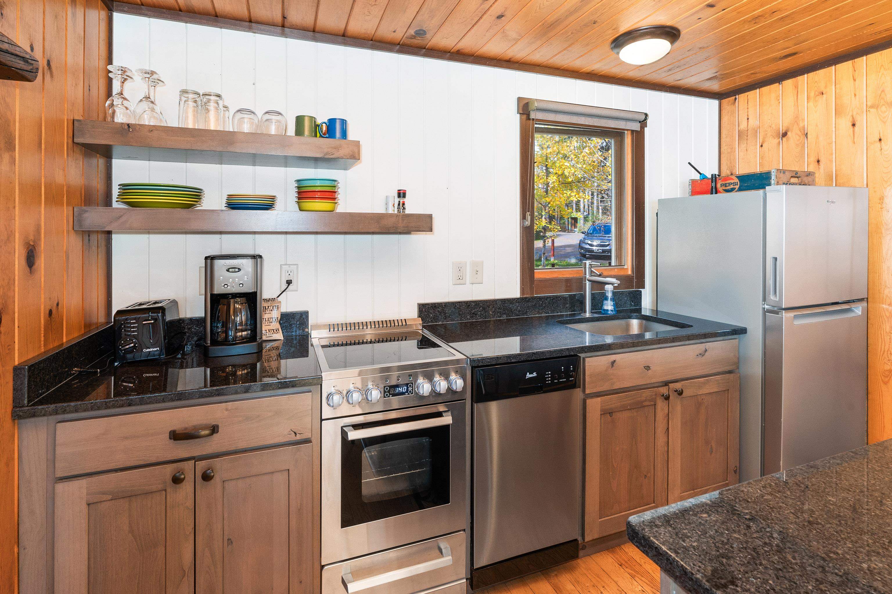 540 Old North Shore Road, Unit 7 Two Harbors, MN 55616 - Photo 15 of 61 Kitchen with stainless steel appliances, open shelves, wooden ceiling, light wood finished floors, and brown cabinetry