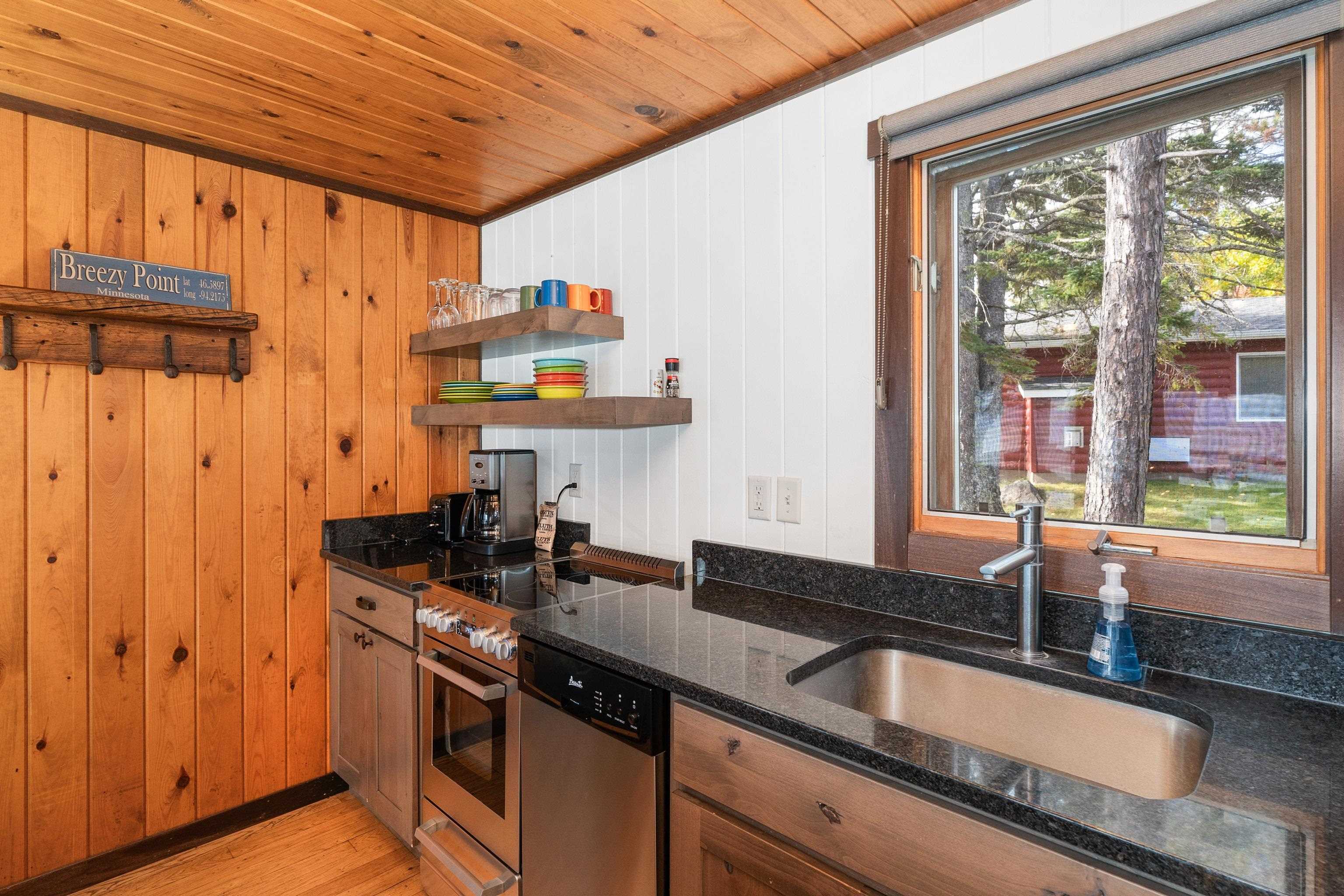 540 Old North Shore Road, Unit 7 Two Harbors, MN 55616 - Photo 16 of 61 Kitchen featuring open shelves, dark stone counters, wooden walls, appliances with stainless steel finishes, and light wood finished floors