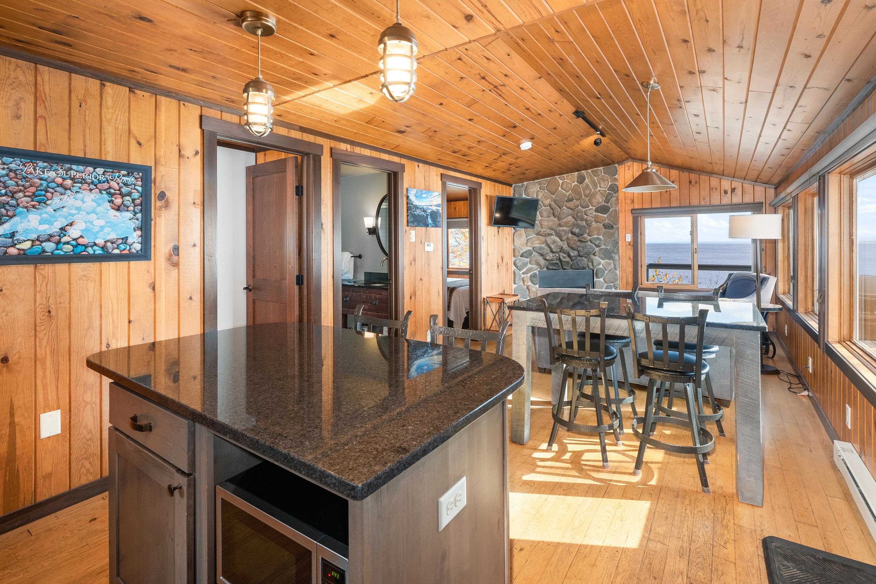 540 Old North Shore Road, Unit 7 Two Harbors, MN 55616 - Photo 18 of 61 Kitchen featuring wooden walls, light wood-style floors, pendant lighting, dark stone counters, and a center island
