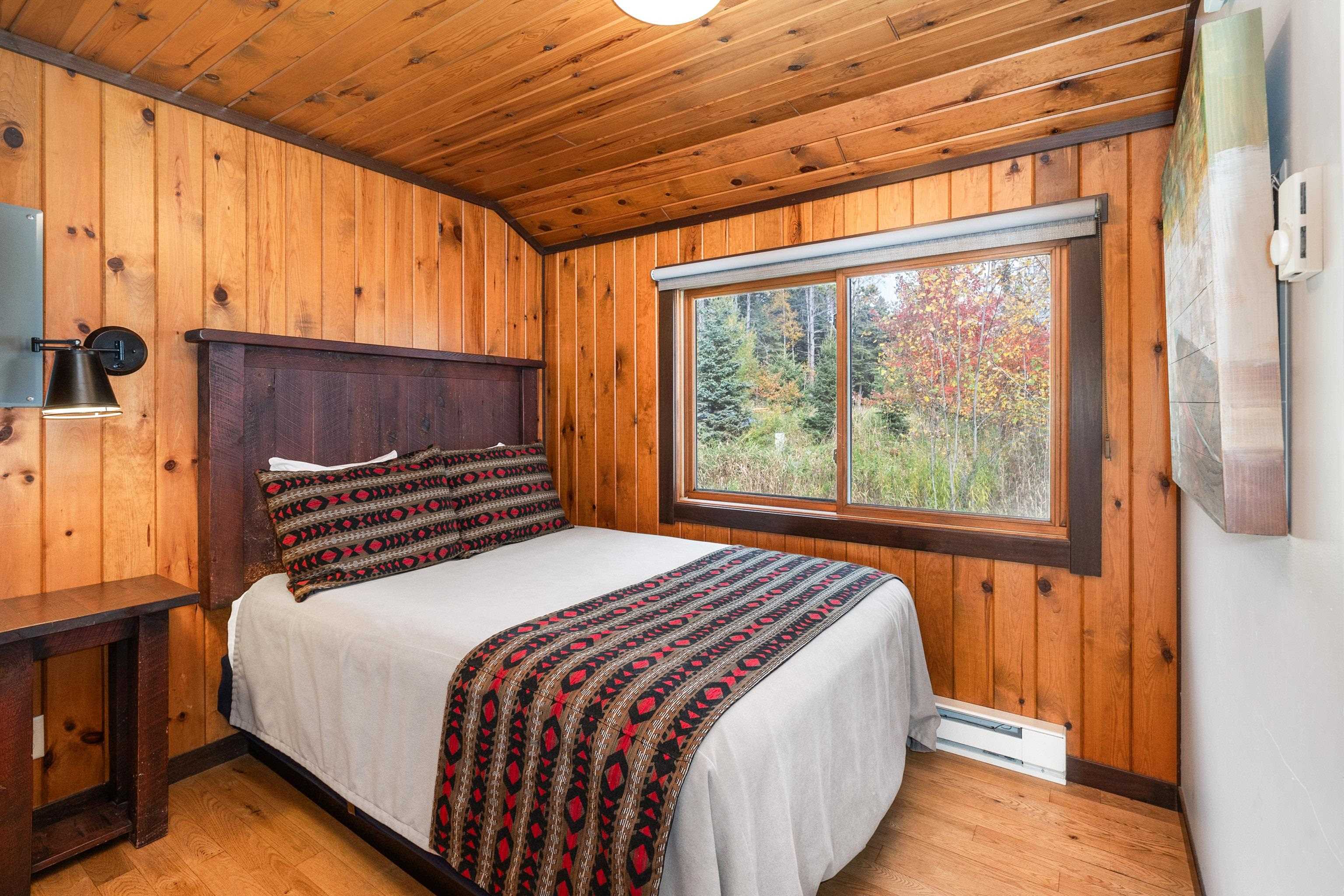 540 Old North Shore Road, Unit 7 Two Harbors, MN 55616 - Photo 26 of 61 Bedroom featuring wood walls, light wood finished floors, a baseboard radiator, and wooden ceiling