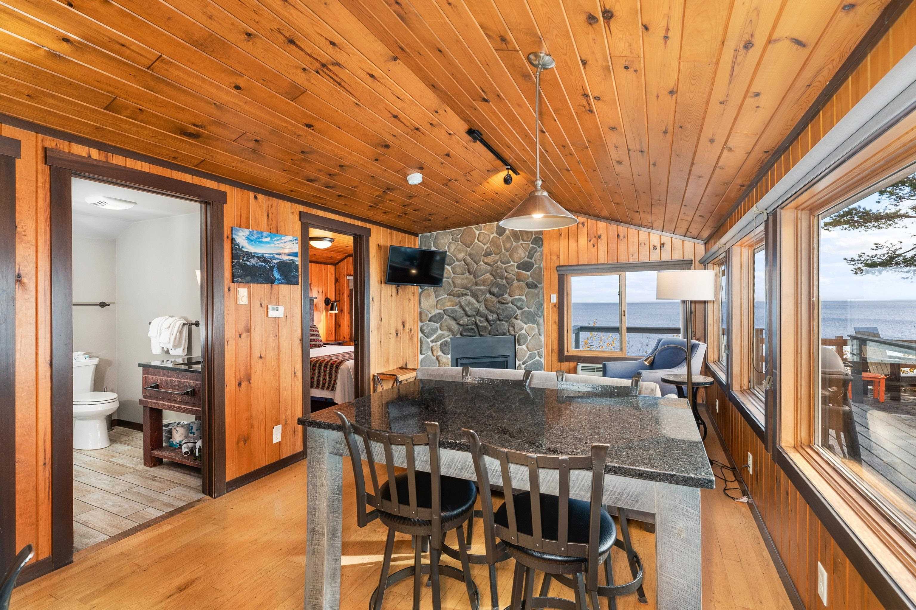 540 Old North Shore Road, Unit 7 Two Harbors, MN 55616 - Photo 9 of 61 Dining space featuring wood walls, light wood-style flooring, lofted ceiling, and a fireplace