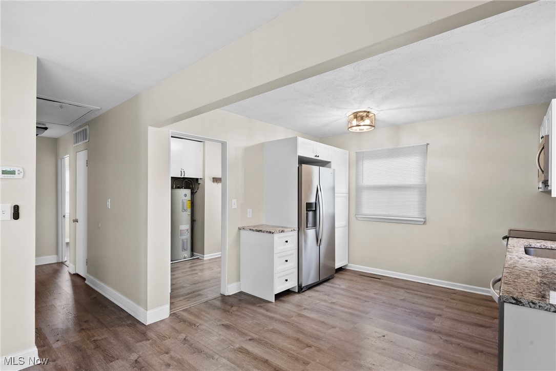 4963 Wake Robin Road Mentor, OH 44060 - Photo 5 of 21 Kitchen with stainless steel appliances, stone counters, light hardwood / wood-style flooring, white cabinets, and water heater