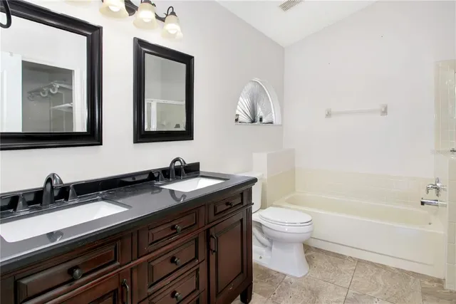 a bathroom with a granite countertop sink a toilet and a bathtub