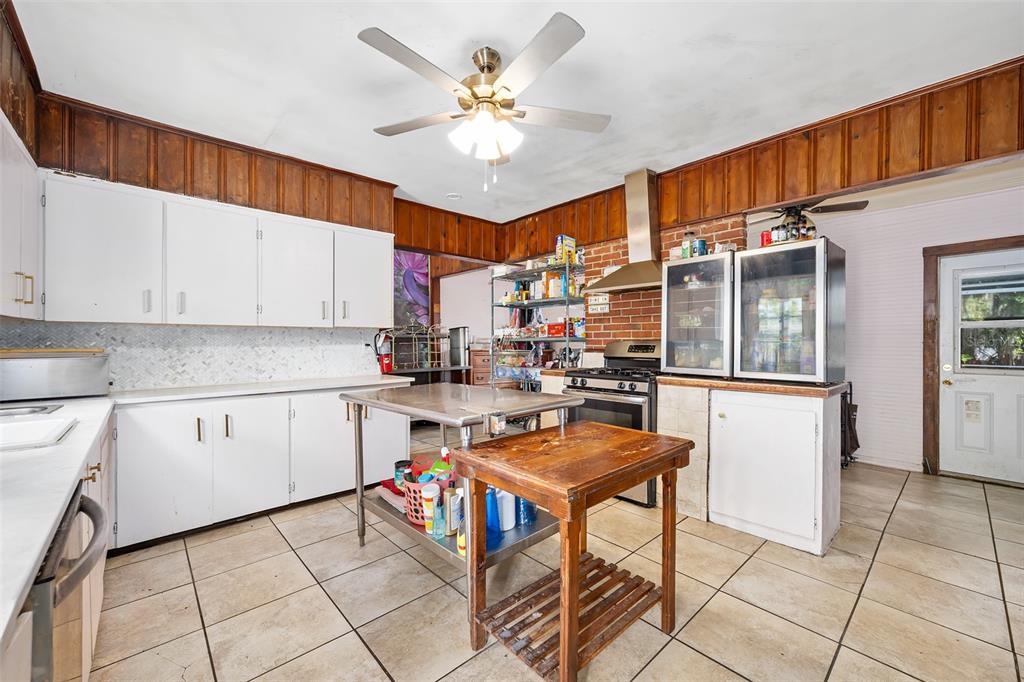 228 West Howry Avenue DeLand, FL 32720 - Photo 34 of 55 a open kitchen with stainless steel appliances kitchen island granite countertop a refrigerator a stove a sink dishwasher and white cabinets with wooden floor