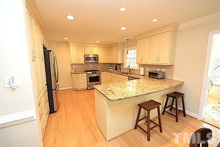 4229 Rowan Street Raleigh, NC 27609 - Photo 9 of 30 a kitchen with stainless steel appliances granite countertop a table chairs and a refrigerator