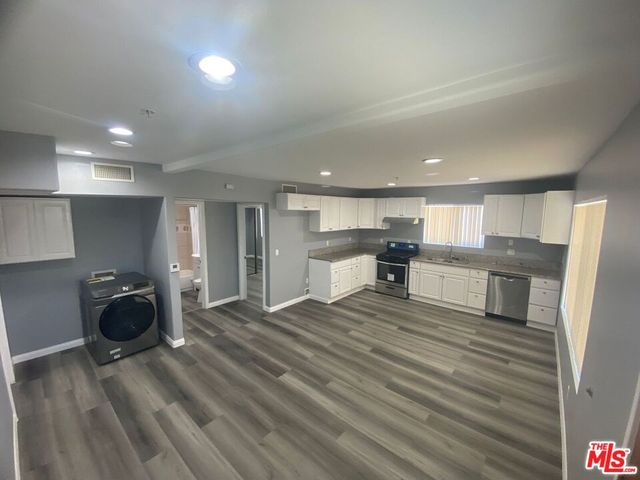 a large kitchen with white cabinets and stainless steel appliances