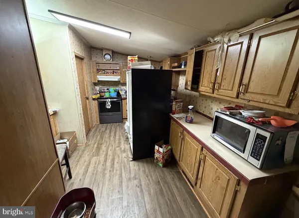 a view of a kitchen with refrigerator and wooden floor