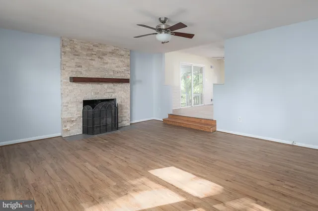 a view of empty room with fireplace and wooden floor