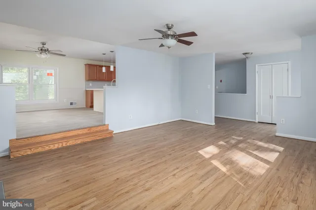 a view of a room with wooden floor and a ceiling fan